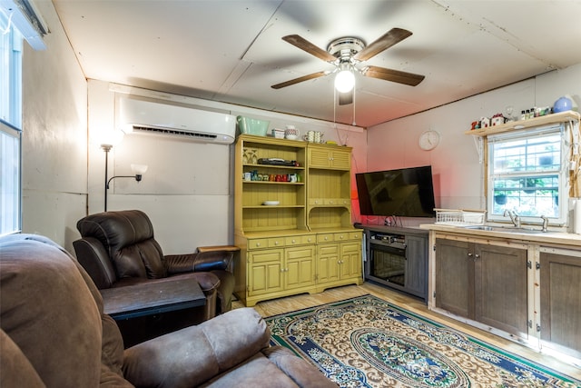 living room with light hardwood / wood-style floors, an AC wall unit, ceiling fan, and sink