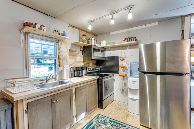 kitchen with appliances with stainless steel finishes, light brown cabinetry, light hardwood / wood-style floors, and sink