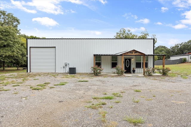 view of outdoor structure featuring cooling unit, a porch, and a garage