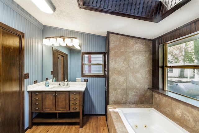 bathroom featuring a tub to relax in, vanity, a textured ceiling, crown molding, and wood-type flooring