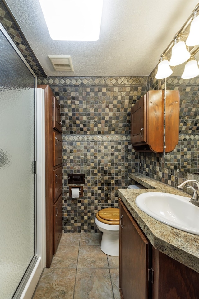 bathroom featuring tile walls, walk in shower, vanity, and toilet