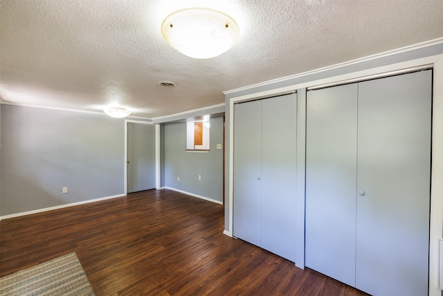 unfurnished bedroom with two closets, a textured ceiling, and dark hardwood / wood-style floors