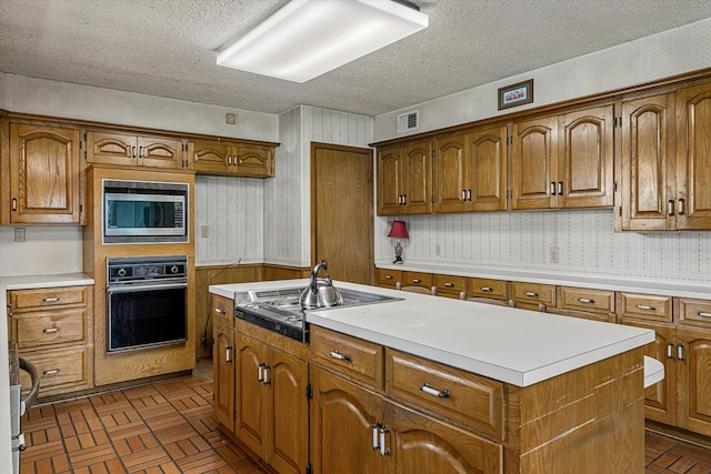 kitchen featuring stainless steel appliances, a textured ceiling, and a kitchen island