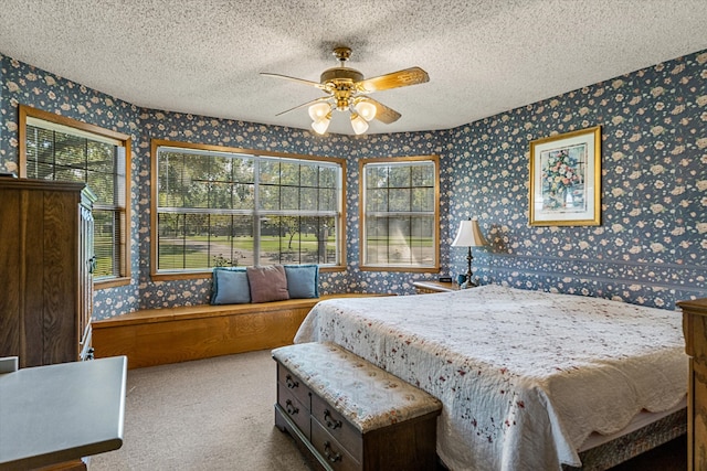 bedroom featuring ceiling fan, light colored carpet, a textured ceiling, and multiple windows