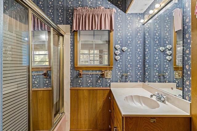 bathroom featuring enclosed tub / shower combo, wooden walls, and vanity