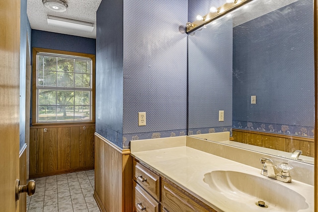 bathroom featuring vanity, wood walls, and a textured ceiling