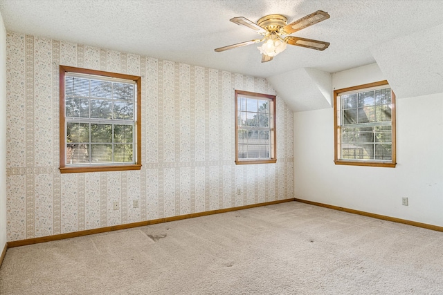 bonus room featuring ceiling fan, a textured ceiling, vaulted ceiling, and a healthy amount of sunlight