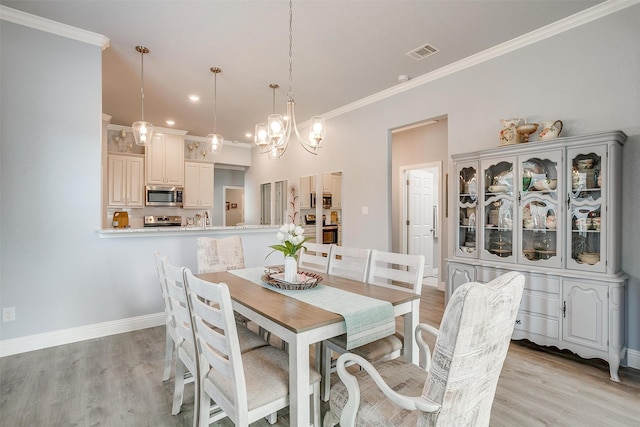 dining area with an inviting chandelier, light wood-type flooring, and ornamental molding