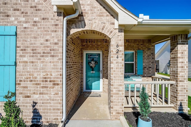 view of exterior entry featuring covered porch