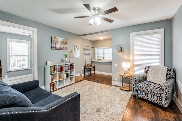 living room featuring a ceiling fan, baseboards, and wood finished floors