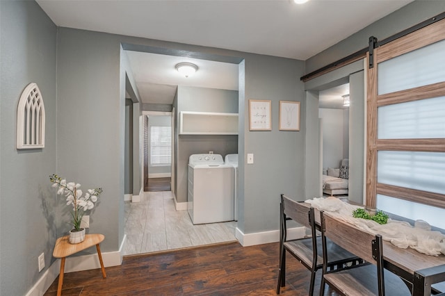 interior space featuring a barn door, laundry area, wood finished floors, baseboards, and independent washer and dryer