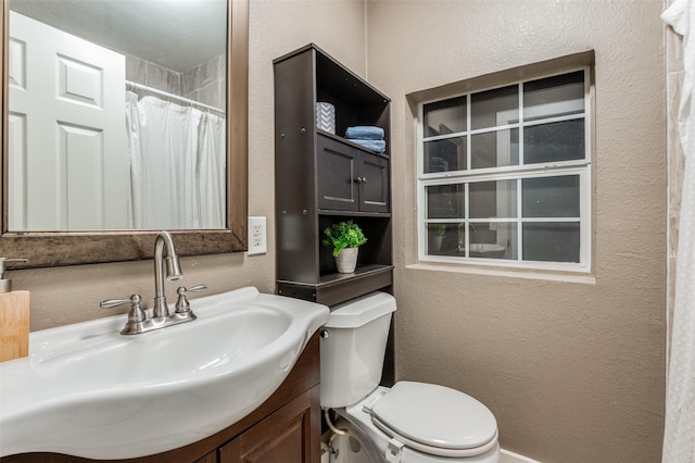 bathroom featuring toilet, vanity, a shower with shower curtain, and a textured wall