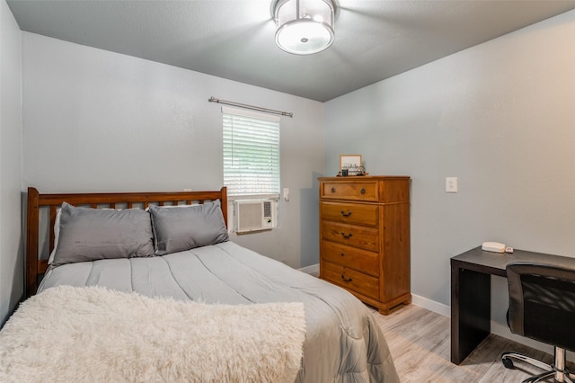 bedroom featuring light wood-type flooring, cooling unit, and baseboards