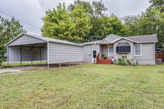 view of front of home with a detached carport, fence, a front lawn, and central AC unit