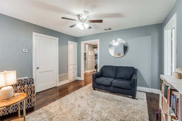 living area with a ceiling fan, dark wood finished floors, visible vents, and baseboards