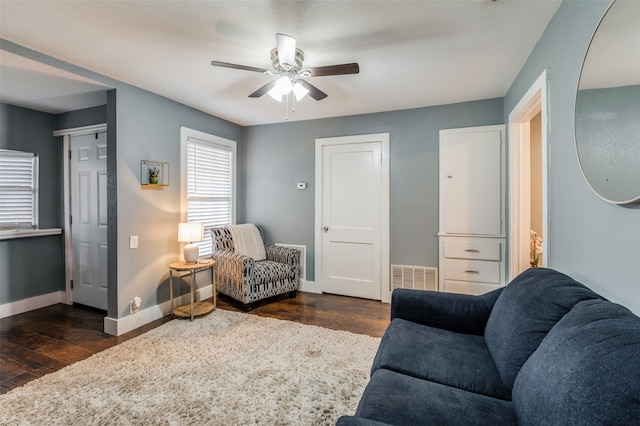 living room featuring dark wood-style floors, visible vents, baseboards, and a ceiling fan