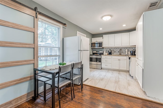 kitchen with stainless steel appliances, visible vents, white cabinets, light countertops, and tasteful backsplash