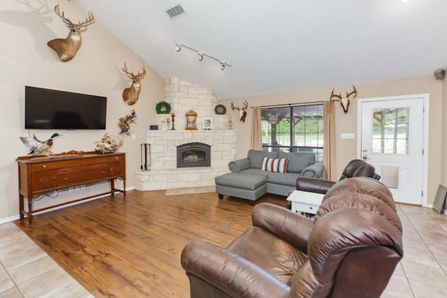 living room featuring a fireplace, track lighting, light wood-type flooring, and lofted ceiling