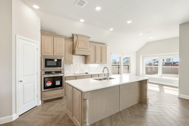 kitchen featuring built in microwave, sink, custom exhaust hood, stainless steel oven, and a center island with sink