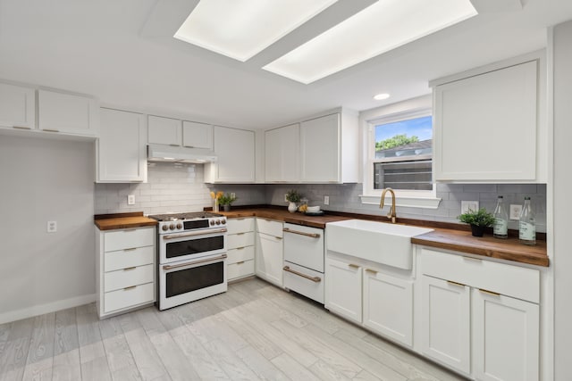 kitchen featuring double oven range, white cabinetry, sink, and wooden counters