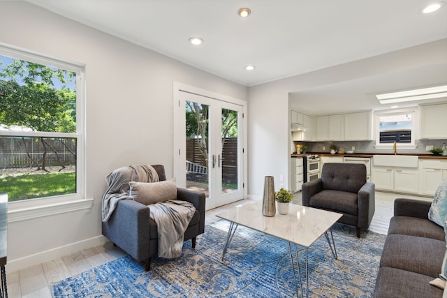 living room with light hardwood / wood-style floors, french doors, and sink