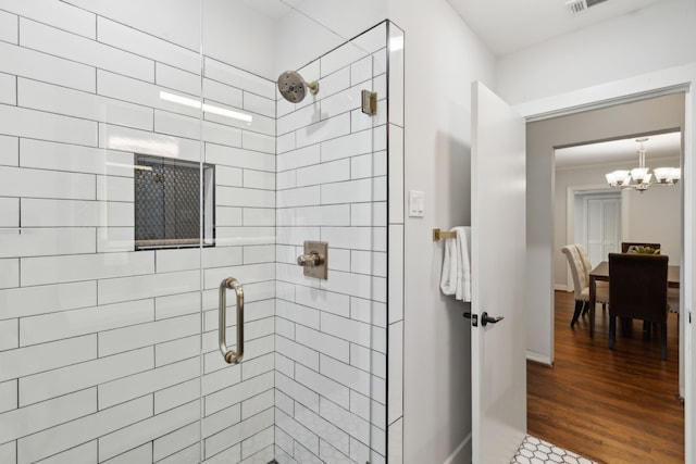 bathroom featuring a shower with door, hardwood / wood-style floors, and a notable chandelier