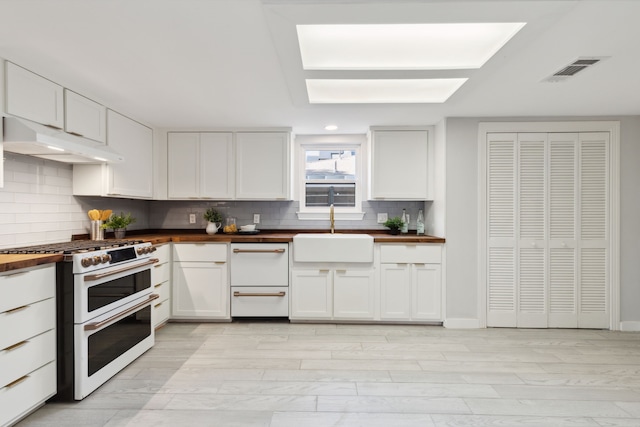 kitchen featuring high end white range, white cabinetry, and butcher block counters