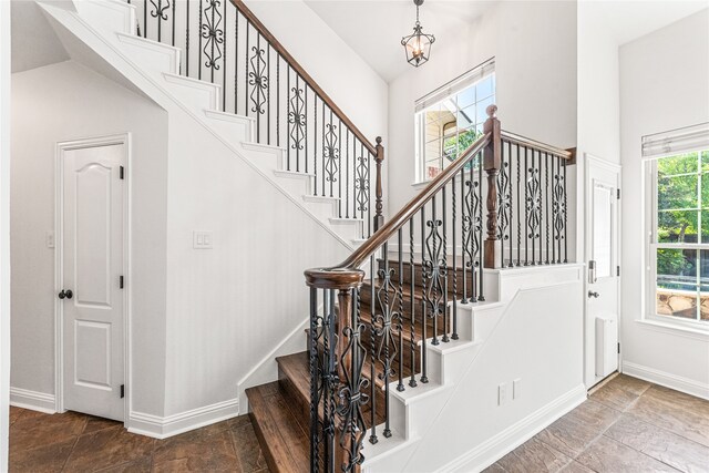 stairs with an inviting chandelier, plenty of natural light, and vaulted ceiling