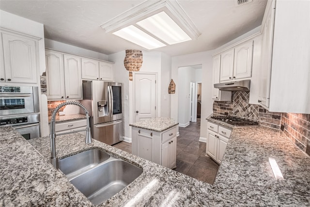 kitchen featuring light stone counters, sink, white cabinets, a kitchen island, and appliances with stainless steel finishes