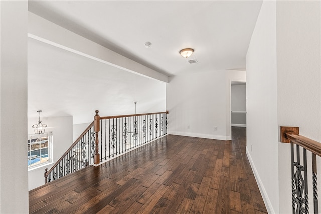 hall with a notable chandelier and dark hardwood / wood-style flooring