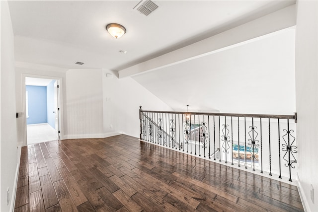 spare room featuring vaulted ceiling with beams and hardwood / wood-style floors