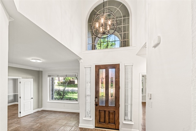 foyer with crown molding, a chandelier, and a high ceiling