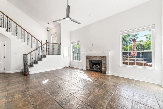 unfurnished living room with a fireplace, ceiling fan, and high vaulted ceiling