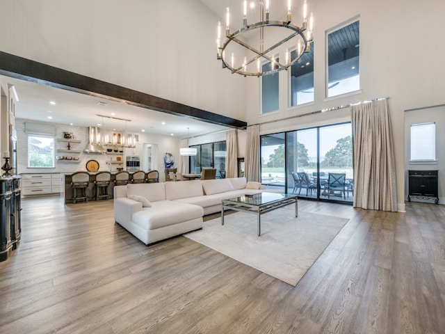 living room with light hardwood / wood-style flooring, a high ceiling, a chandelier, and beamed ceiling