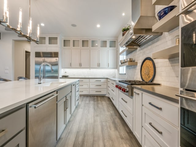 kitchen with island range hood, decorative light fixtures, appliances with stainless steel finishes, and white cabinetry