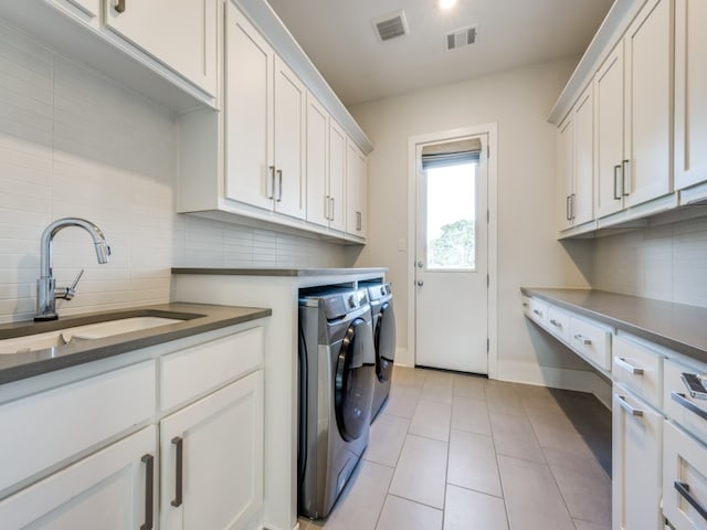 clothes washing area with light tile patterned floors, sink, washer and dryer, and cabinets