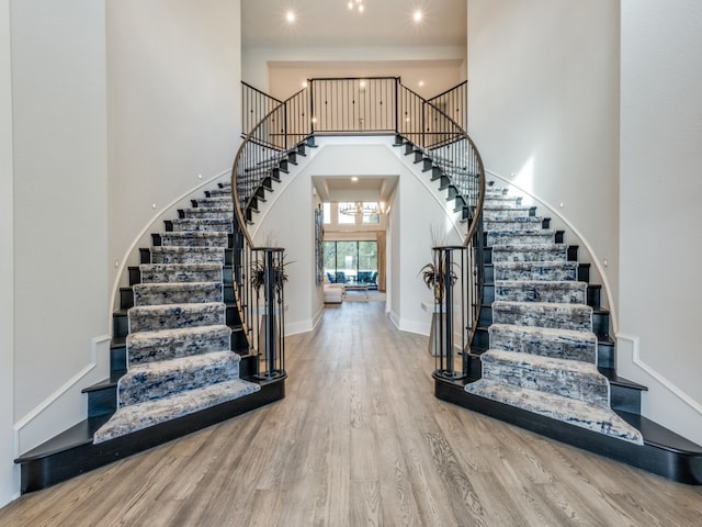 entryway featuring wood-type flooring and a towering ceiling