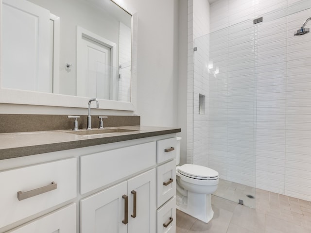 bathroom featuring vanity, tile patterned floors, toilet, and tiled shower