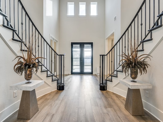 entrance foyer featuring french doors, hardwood / wood-style floors, and a high ceiling