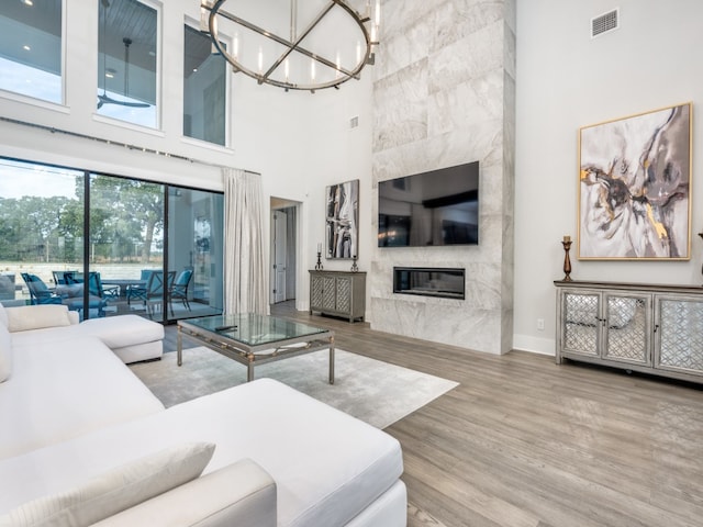 living room with an inviting chandelier, a high ceiling, a large fireplace, and hardwood / wood-style flooring