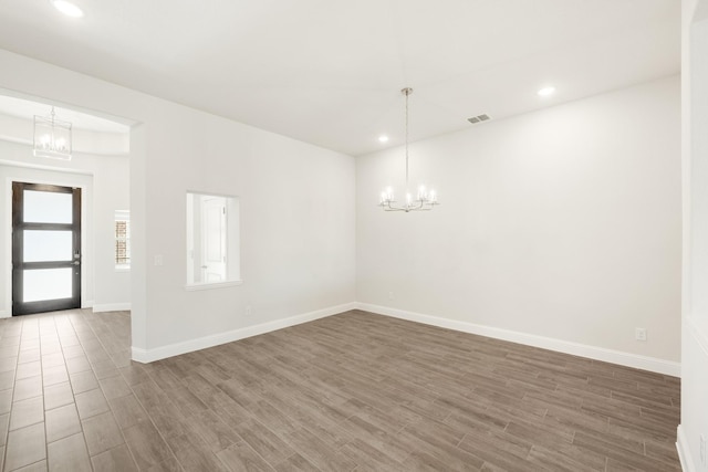 unfurnished room featuring an inviting chandelier and hardwood / wood-style flooring