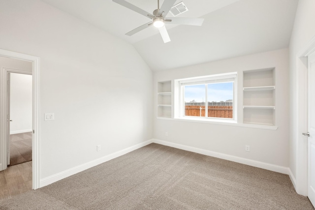 carpeted spare room with ceiling fan, lofted ceiling, and built in shelves