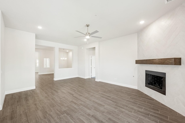 unfurnished living room with ceiling fan with notable chandelier and dark wood-type flooring