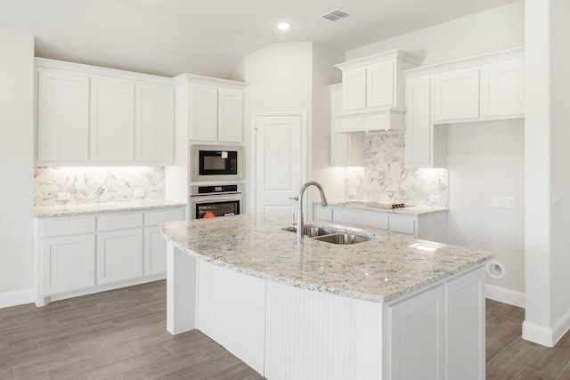 kitchen featuring backsplash, black appliances, sink, a kitchen island with sink, and white cabinets