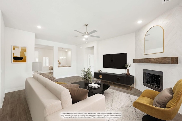 living room with hardwood / wood-style flooring, ceiling fan with notable chandelier, and a fireplace