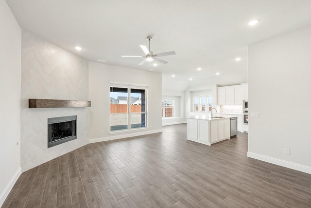 kitchen with sink, white cabinets, light stone counters, and an island with sink