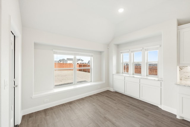 unfurnished dining area featuring vaulted ceiling and hardwood / wood-style floors