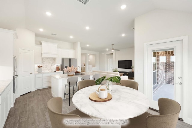 dining area featuring hardwood / wood-style flooring, ceiling fan, and vaulted ceiling