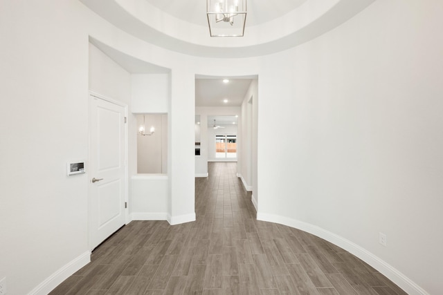 hallway with wood-type flooring and an inviting chandelier