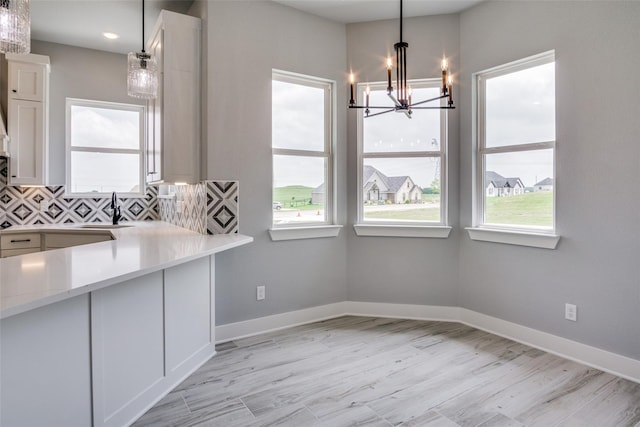 kitchen featuring white cabinets, hanging light fixtures, sink, tasteful backsplash, and a chandelier